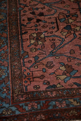 Corner of a fine Lilihan rug with a raspberry red field, arabesque vines, and an indigo floral border.