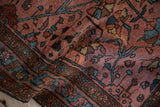 High luster on the folded wool pile of an antique Lilihan rug, showing even wear and floral details in raspberry and blue.