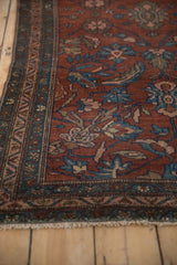 Thin meandering vine border beside the burgundy red field of an antique Persian rug.