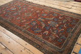 Angled view of an antique Mehriban rug highlighting its time-softened texture and sprawling floral vinery.