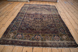 Antique Kermanshah rug corner with green-gold border, turtle samovar arabesques, and tattered fringe.