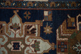 Vintage Heriz rug fragment detail: navy field with geometric motifs and a meandering vine blossom border.