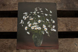 Vintage lithograph of white daisies in a glass vase against a dark background, showing paper creases.