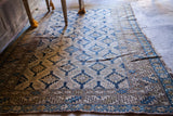 Geometric blue diamond patterns and worn texture of an antique Caucasian rug.