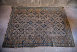Faded neutral beige and blue geometric design on a worn antique Caucasian rug.