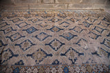 Worn texture and stepped geometric patterns in blue and neutral on an antique Caucasian rug.