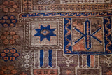 Hand-knotted Belouch rug detail: geometric patterns in deep blue, terracotta, and subtle purple.