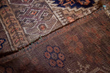 Distinctive geometric pattern with rich purple and nutty brown tones on the Belouch rug.