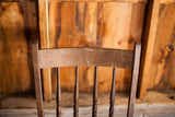 Back of antique oak chair showing four spindles, rich patina, and paint splatters.