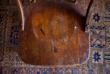 Antique wooden oak chair seat featuring warm brown patina, grain, and white paint splatters.