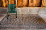 Earthtone Caucasian rug, repeating boteh on charcoal field, geometric borders, tattered end.