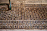 Close-up of repeating geometric boteh pattern in earth tones and soft blue on charcoal.