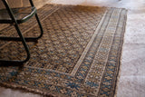Vintage Earthtone Caucasian rug with geometric border, repeating boteh pattern, and tattered fringe.