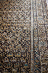 Repeating earthtone and blue boteh motifs on charcoal field, adjacent geometric Caucasian border.