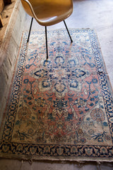 Detail of blanched antique Persian Dorokhsh rug with worn pile and tattered fringe.