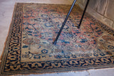 Unique alicorn vine design on the faded coral and blue corner of this worn Persian rug.