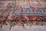 Tattered edge of a late 19th century Caucasian antique rug, featuring vibrant geometric motifs with heavy wear.