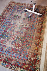 Antique Caucasian rug corner with vibrant geometric patterns, brilliant colors, and visible exposed foundation.