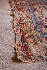 Frayed edge of an antique Caucasian rug revealing visible hand-knotted foundation and geometric patterns.