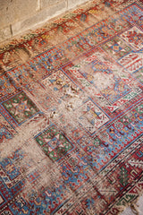 Antique Caucasian rug close-up, showing heavy wear, holes, and bright geometric patterns.