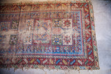 Storied wear revealing geometric patterns and vibrant colors of the antique Caucasian rug.