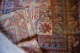 Visibly worn pile and vibrant geometric patterns on this antique Caucasian rug.