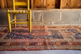 Geometric patterns of a worn antique Kazak prayer rug section.