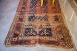 Worn geometric patterns of a late 19th century Kazak rug, in deep blue, red, and muted peach.