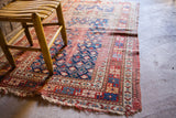 Saturated red and blue geometric patterns on a worn late 19th-century Kazak Prayer rug.