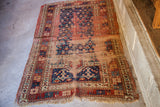 Geometric blue and red patterns with significant pile loss on the antique Kazak rug.