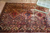 Close-up of worn geometric tribal rug showing rich warming colors and authentic character.