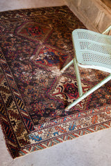 Close-up of worn tribal geometric rug border, featuring brilliant red and blue patterns, and fringe.