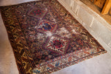 Late 19th-century tribal rug corner, displaying worn geometric motifs and warm tones.