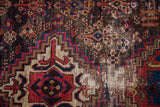 Close-up of worn pile and exposed foundation showing geometric tribal motifs and warming colors.