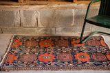 Antique Persian Senneh rug with dark blue ground, rust geometric patterns, and tattered ends.