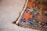 Heavy tattered fringe and intricate pattern detail of this antique Senneh rug corner.