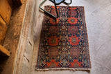 Worn fringe and geometric brick red, navy, gold patterns on an antique Persian Senneh rug.