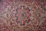 Antique Kerman rug with scalloped medallion, cochineal red, ivory, dark blue, and worn exposed foundation.