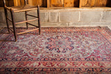 Antique Kerman rug's deeply scalloped medallion and cochineal red Safavid-inspired border.