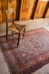 Worn antique Kerman rug with a scalloped medallion, Safavid border, and cochineal red tones.