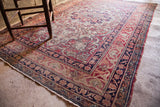 Antique Kerman rug corner showing worn Safavid border in cochineal red, ivory, dark blue.