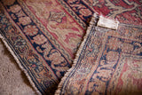 Antique Kerman rug detail showing worn cochineal red pile, Safavid border, and hand-knotted construction.