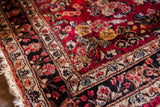 Tightly knotted Sarouk runner corner displaying rich red curvilinear floral motifs and dark border.