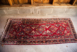 Semi-antique Red Sarouk runner with intricate floral design, vibrant colors, and fringed edge.