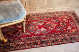 Painted American Sarouk runner, deep red field, intricate floral patterns in cream and blue.