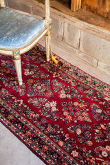 Vibrant ruby red Sarouk runner, densely painted with floral patterns, dark border.