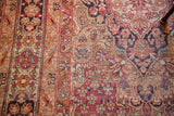 Intricate floral design and age-softened pile in dark blue and cochineal red on this Kerman rug.