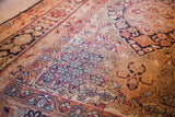 Antique Kerman rug with light blue and cochineal red floral motifs, showing gentle wear.