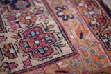Antique Kerman rug's hand-knotted texture, cochineal red and dark blue floral patterns.