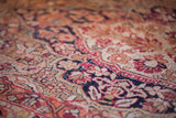 Softened hand-knotted pile of antique Kerman rug, showing dark blue, cochineal, and ivory floral design.